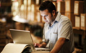 man working at warehouse looking at computer