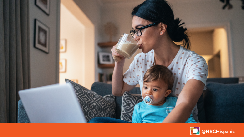 Woman holding baby while working on computer.